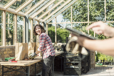 Happy woman looking at man using digital tablet in greenhouse