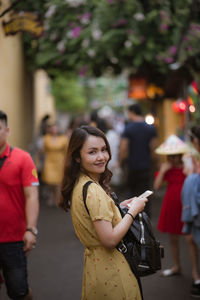 Portrait of beautiful young woman using phone on city street