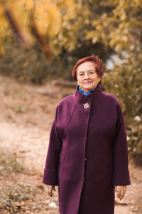 Portrait of young woman standing against tree