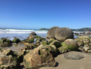 Rocks on beach against clear blue sky