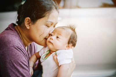 Happy asian family of mother and baby kissing.