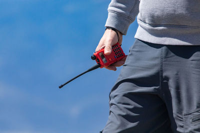 Midsection of man holding umbrella against sky