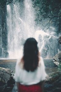 Rear view of woman looking at waterfall