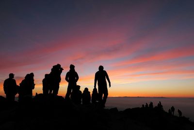 Silhouette people on beach at sunset