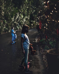 Side view of siblings with push scooters standing on road during christmas