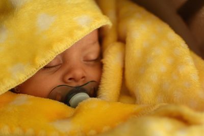 Close-up of newborn lying under blanket