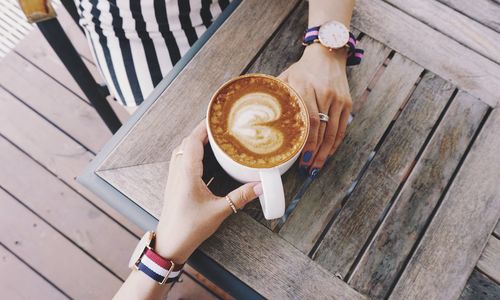 Directly above shot of hands holding coffee cup on table