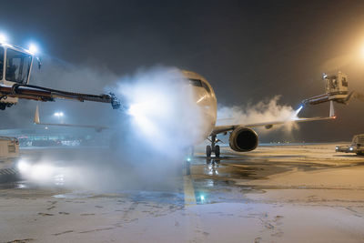 Deicing of airplane before flight. winter frosty night and ground service at airport.