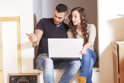 Young woman using laptop while sitting on table