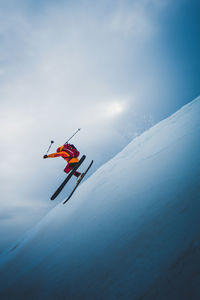 Man flying off ski jump with sun and sky behind him