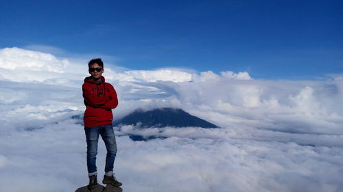 Full length portrait of young man standing against sky