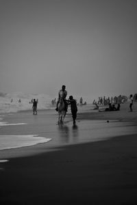People walking on beach against clear sky