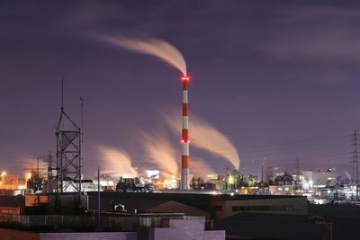 Illuminated factory against sky at night