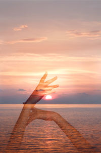 Double exposure of hands and sea during sunset