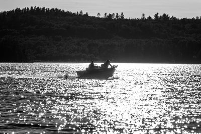 View of people fishing in lake against sky