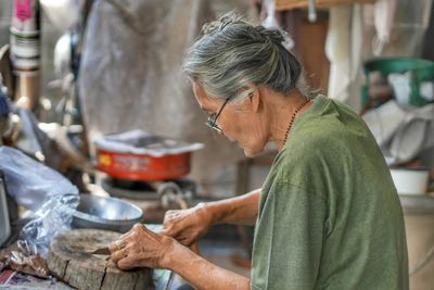 Senior woman cutting on wood at home