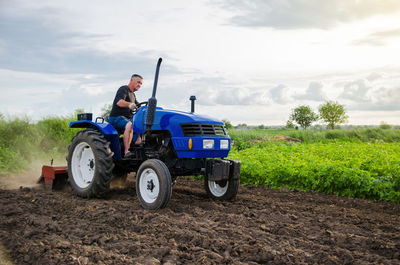 Farmer on tractor cultivates farm field. milling soil, crushing and loosening ground