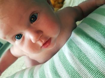 Close-up portrait of cute baby girl lying on bed