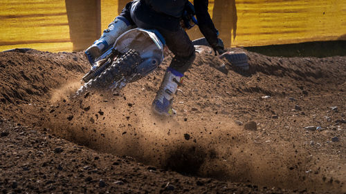 Low section of man riding motorcycle on mud