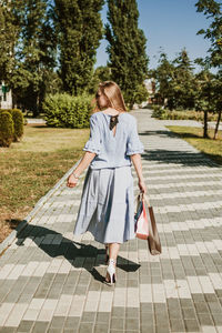 Fashion pretty cool young girl with shopping bags walking on a city street. young blonde 