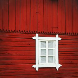 Window with white frame on red wooden wall