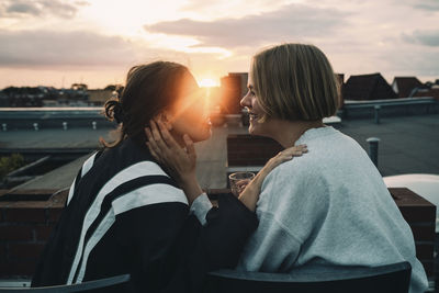 Rear view of mother with daughter against sky during sunset