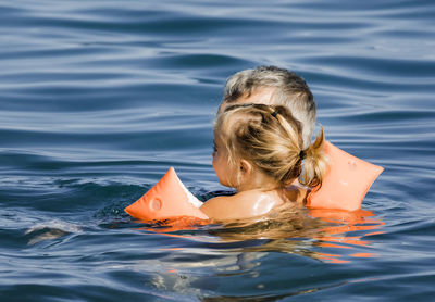 Close-up of cute girl with grandfather in sea