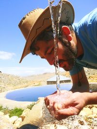 Close-up of man drinking water against sky