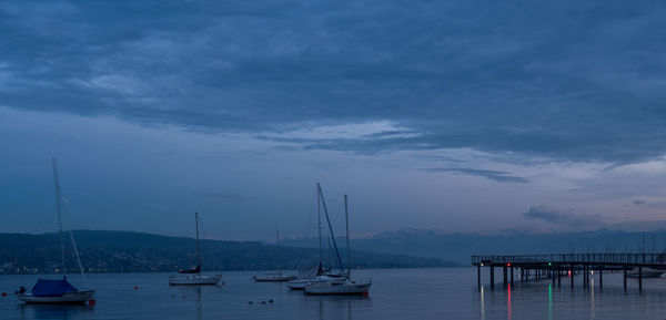 Sailboats moored in harbor against sky