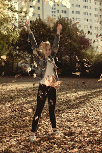 Woman throwing autumn leaves on field