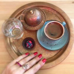 High angle view of woman holding coffee cup on table