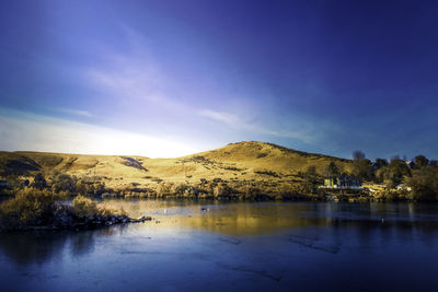 Scenic view of lake by mountains against sky