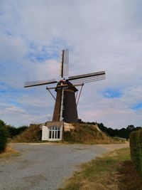 Traditional dutch mill on field against sky