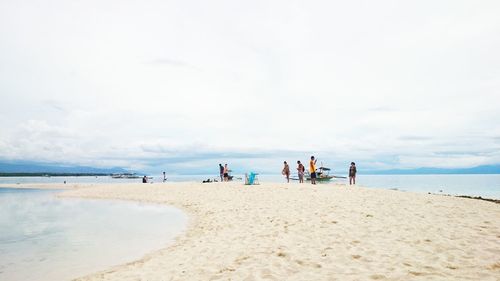 People at beach against cloudy sky