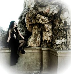 Young woman sitting statue against sky