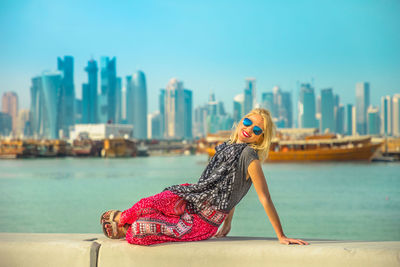 Portrait of woman wearing sunglasses in city against clear sky