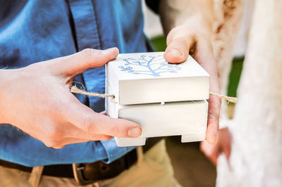 A white wooden box in the hands of a man. handmade gift packaging in rustic style