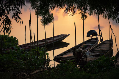 People sitting on shore against sky during sunset