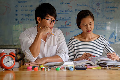 Friends studying with school supplies on table at home