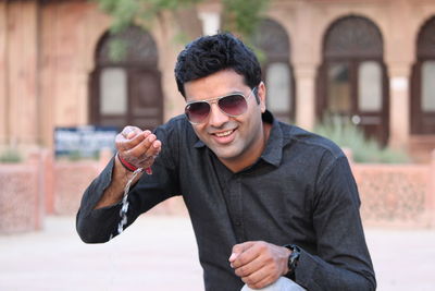 Portrait of young man wearing sunglasses standing outdoors