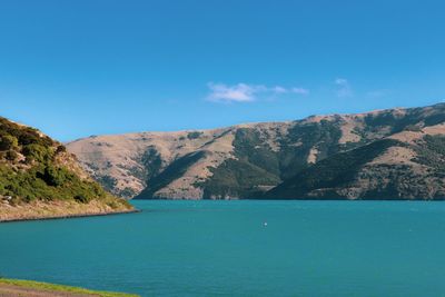 Scenic view of sea and mountains against blue sky