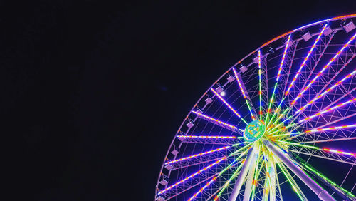 Low angle view of illuminated ferris wheel against sky at night