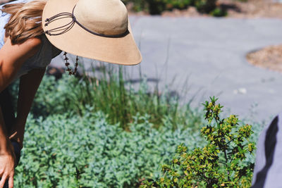 Woman in hat bending by plants