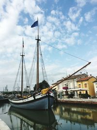 Sailboats moored at harbor against sky