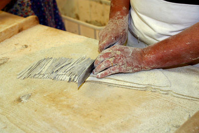 Midsection of woman cutting dough on table