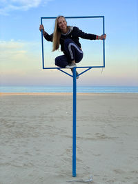 Low angle view of woman sitting in the frame on beach against sky