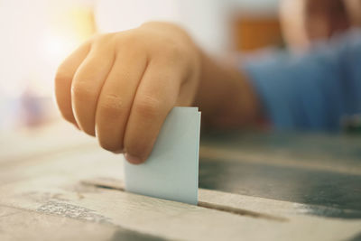 Close-up of hand inserting paper in ballot box