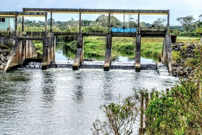 Bridge over river in forest against sky