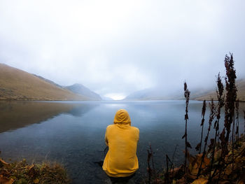 Rear view of man looking at lake against sky