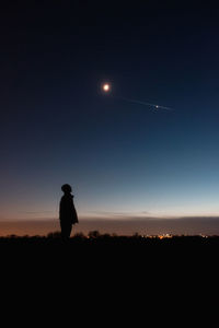 Silhouette man standing on field against sky at night